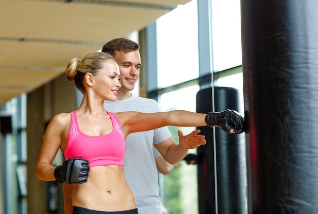 sport, fitness, stile di vita e concetto di persone - donna sorridente con personal trainer boxe in palestra