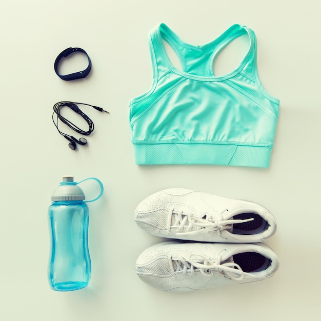 Sport, fitness, stile di vita sano e concetto di oggetti - abbigliamento sportivo femminile, orologio cardiaco, auricolari e set di bottiglie