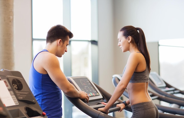 sport, fitness, stile di vita, tecnologia e concetto di persone - donna con trainer che si allena sul tapis roulant in palestra