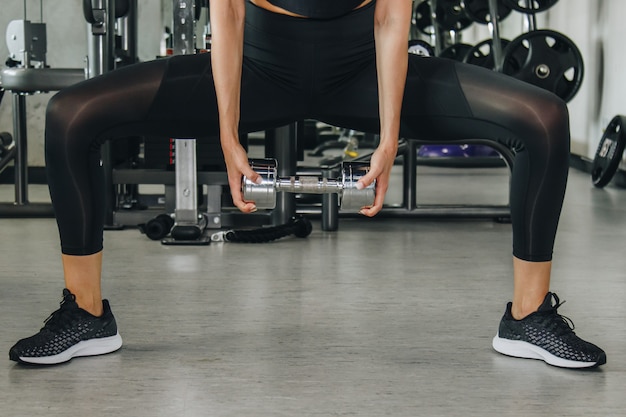 Sport, forma fisica, culturismo, sollevamento pesi e concetto della gente - vicino su della donna che flette le armi con la testa di legno in palestra.