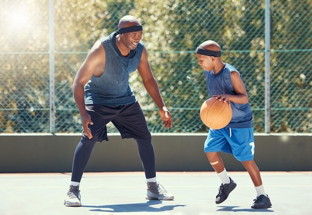 Sport in famiglia e apprendimento del basket con un papà e un figlio che si allenano su un campo all'aperto per il tempo libero, fitness e divertimento Uomo di colore e bambino che fanno esercizio e si allenano giocando a un gioco per la salute e l'allenamento