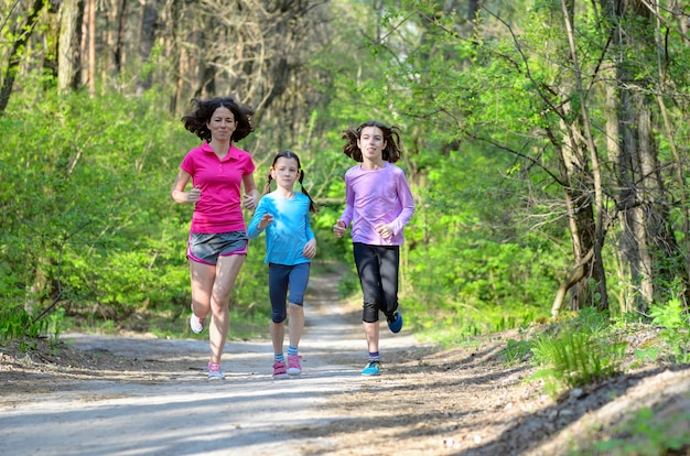 Sport per famiglie, madre attiva felice e bambini che pareggiano all'aperto, correndo nella foresta