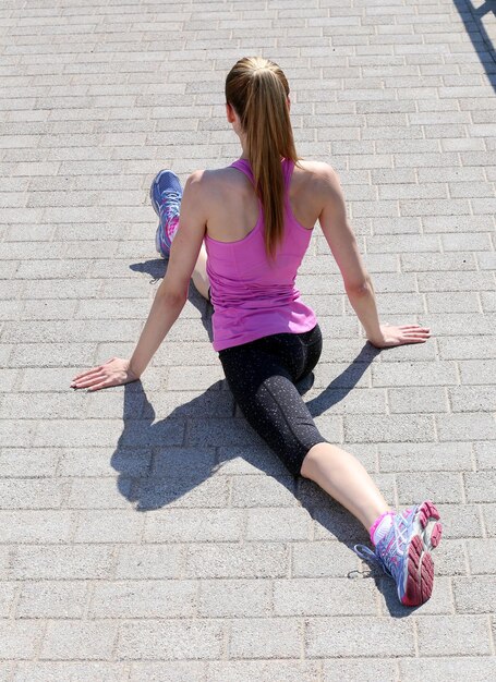 Sport Ragazza attraente per strada che si allunga le gambe