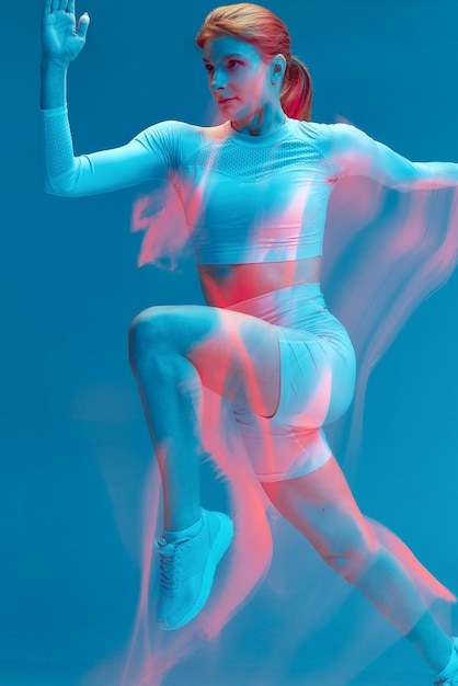 Sport ragazza in esecuzione su sfondo blu luce al neon colorata lunga esposizione sport professionale