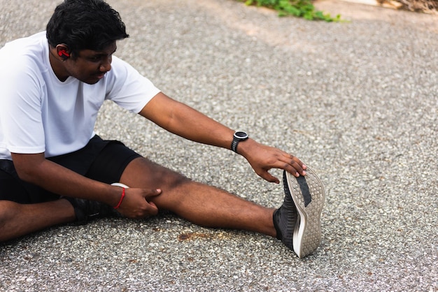 Sport runner uomo nero indossare orologio lui seduto pull toe piedi stretching gambe e ginocchio