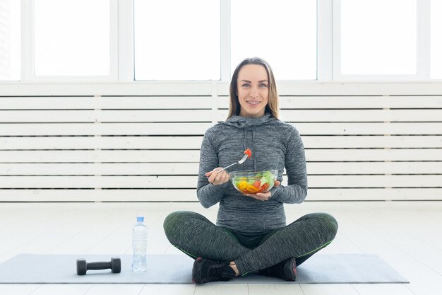 Sport, sano, concetto di persone - Ragazza con insalata e manubri dopo l'allenamento fitness