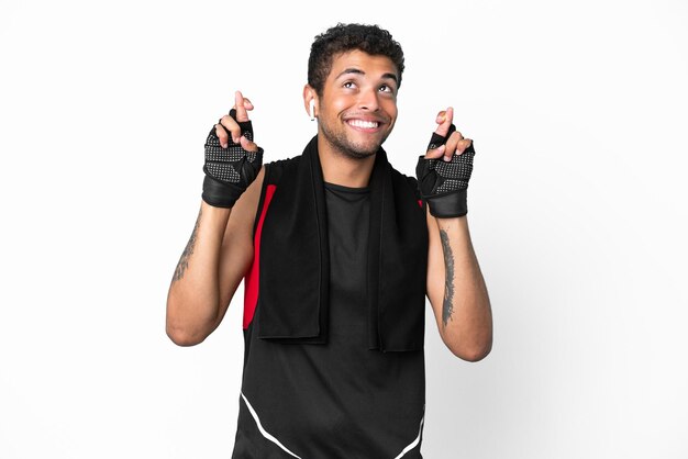 Sport uomo brasiliano con asciugamano isolato su sfondo bianco con le dita incrociate