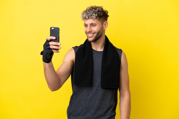 Sport uomo caucasico isolato su sfondo giallo facendo un selfie