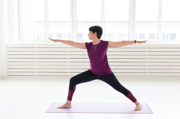 Sport, yoga, concetto di persone - Donna di mezza età sportiva che pratica yoga al chiuso