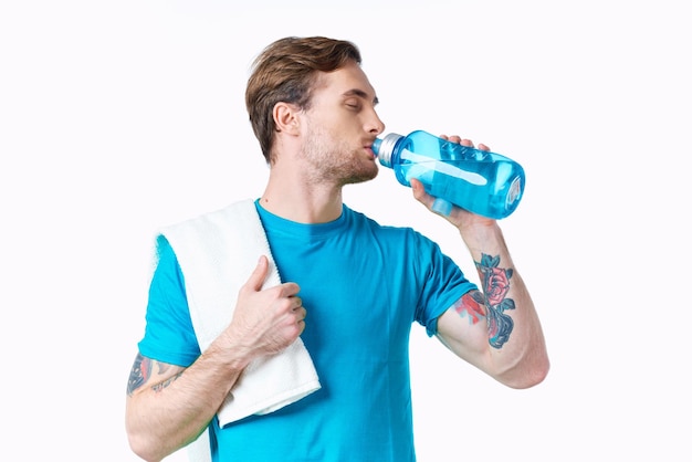 Sportista in maglietta blu con una bottiglia d'acqua nel fiume e tatuaggio sfondo bianco modello di fitness foto di alta qualità