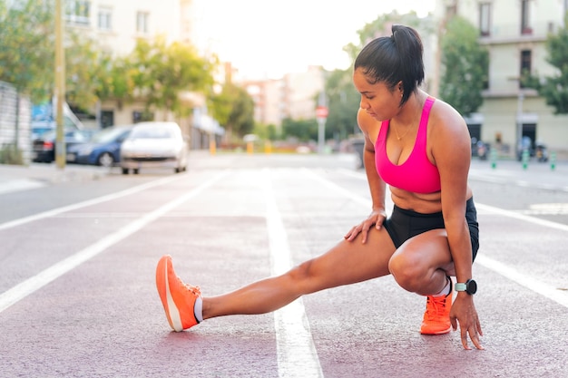 Sportiva che allunga le gambe sulla pista di atletica