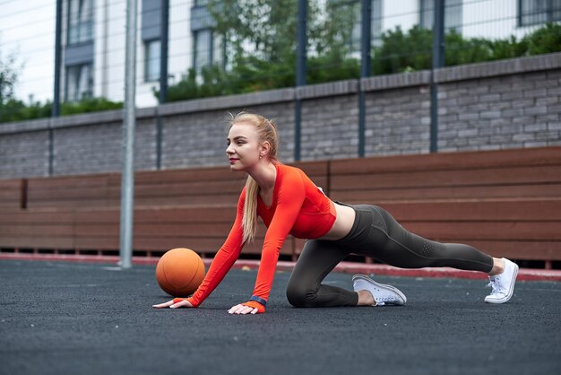 Sportiva che fa esercizio di allungamento delle gambe con palla medica Donna in forma che si esercita con la palla in allenamento in palestra