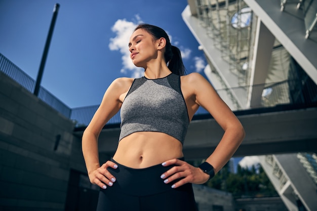 Sportiva emotiva in piedi in primo piano e tenendo gli occhi chiusi dal sole