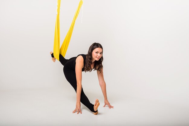 Sportiva esegue esercizi di stretching con un'amaca su una parete bianca