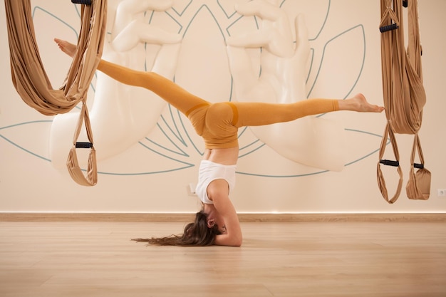 Sportiva in forma elegante che fa spaccature in verticale allo studio di yoga