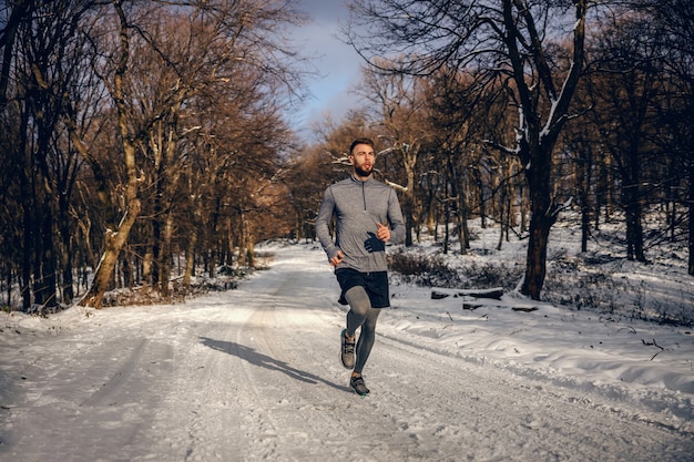 Sportivo a fare jogging in natura sulla neve in inverno. Fitness invernale, fitness nella natura, clima freddo