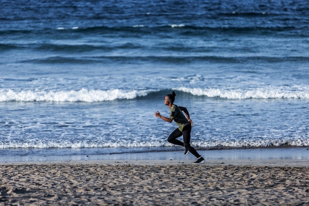 Sportivo afroamericano che corre vicino al mare