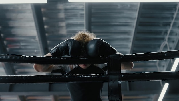 Sportivo apatico in piedi in palestra Combattente confuso che perde battaglia sul ring