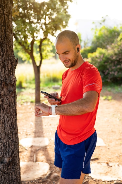 Sportivo che controlla il suo orologio sportivo con il suo telefono cellulare