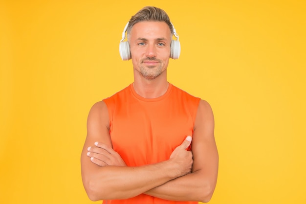 Sportivo o atleta sano. Sport e fitness. Musica per il fitness. Lo sportivo ascolta la musica. Allenamento sportivo. Allenamento regolare. Allenatore maturo. Il forte sportivo indossa le cuffie e l'uniforme fitness.