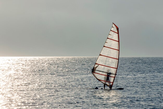 Sportivo praticando il windsurf al tramonto