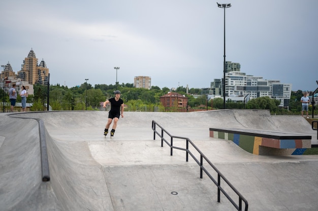 sportivo sui pattini e nel casco che pattina sui pattini a rotelle nello skate park