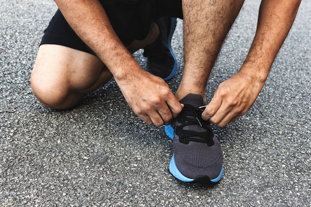 Sportman del primo piano che lega le scarpe da corsa