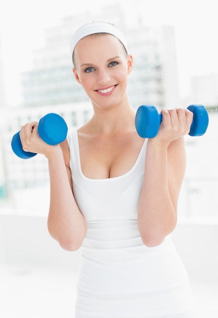 Sportswoman motivato che trasporta dumbbells