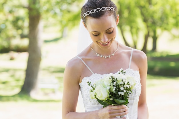 Sposa che esamina il mazzo in giardino