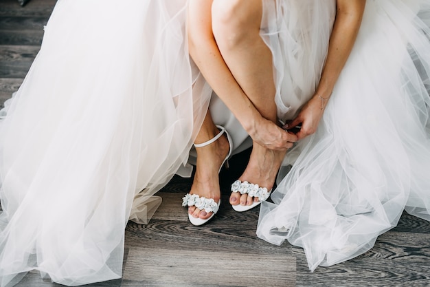 Sposa che indossa un abito da sposa, mettendosi le scarpe.