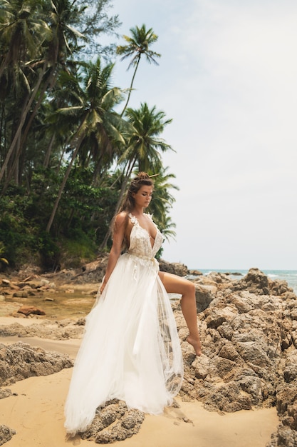 Sposa che porta bello vestito da sposa sulla spiaggia tropicale