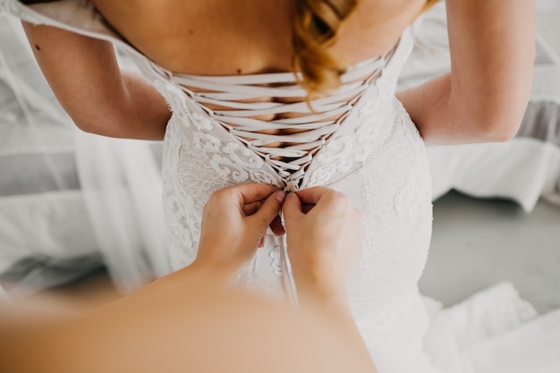 Sposa che si prepara, damigella d'onore che allaccia il corsetto