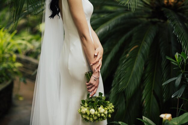 sposa che tiene il bouquet da sposa di rose bianche