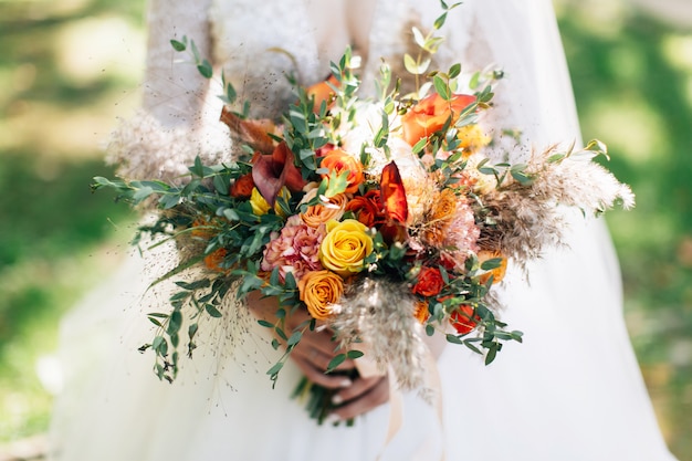 Sposa che tiene il grande mazzo di nozze. Bouquet di fiori autunnali