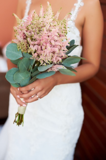 Sposa che tiene un mazzo di fiori in stile rustico, bouquet da sposa