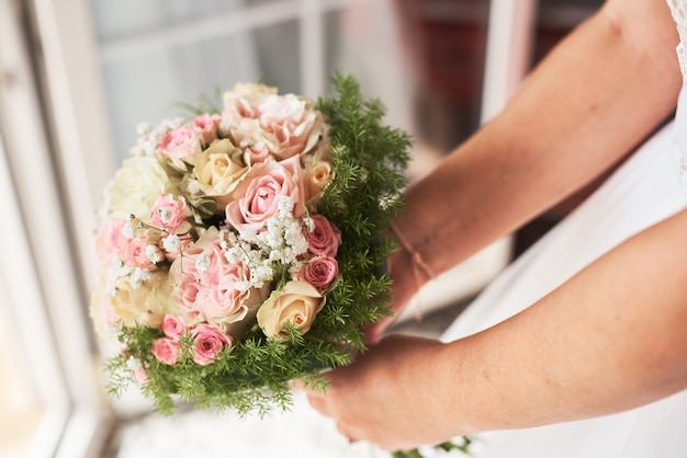 Sposa che tiene un mazzo di rose rosa in stile rustico.