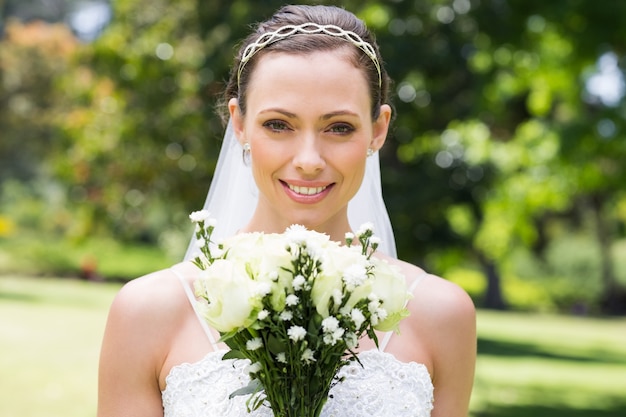 Sposa con bouquet di fiori sorridenti in giardino