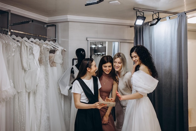 Sposa con gli amici che scelgono l'abito da sposa in boutique
