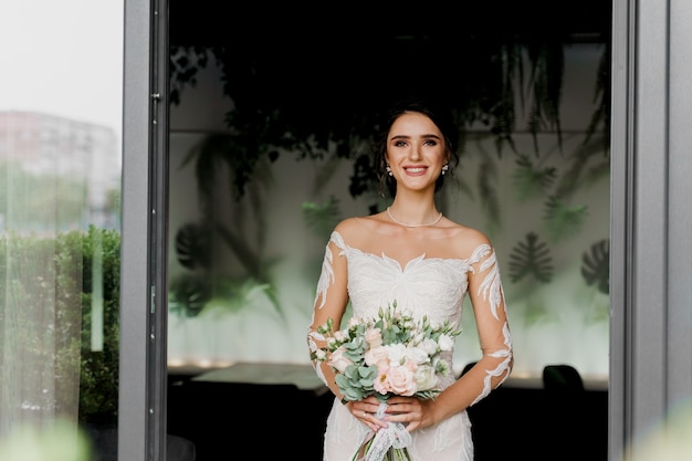 Sposa con sorrisi bouquet da sposa. Ragazza in abito da sposa in un ristorante di lusso.