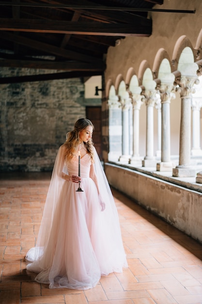 Sposa con una candela accesa tra le mani si alza e guarda il pavimento della loggia di un'antica villa