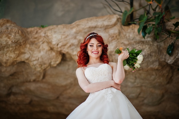 Sposa dai capelli rossi affascinante con il mazzo di nozze