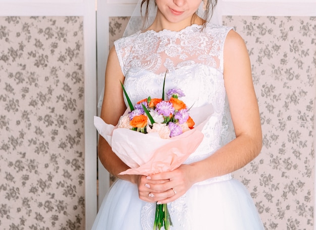 Sposa della donna che tiene i bei fiori del mazzo