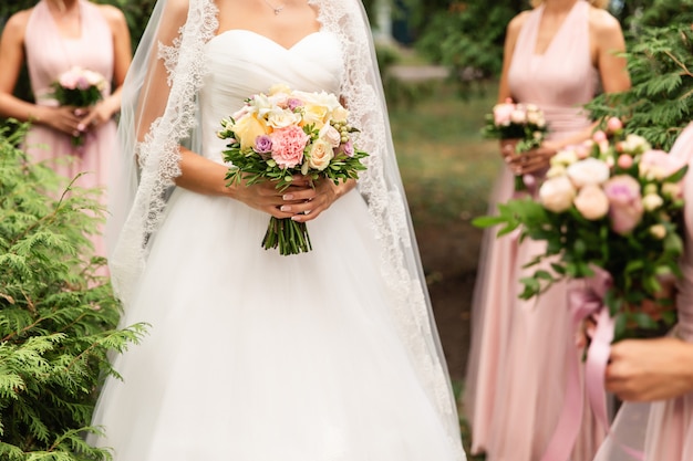 Sposa e damigelle in abiti rosa che posano con i mazzi al giorno delle nozze.