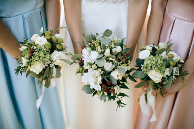 Sposa e le sue amiche che tengono un mazzo di nozze