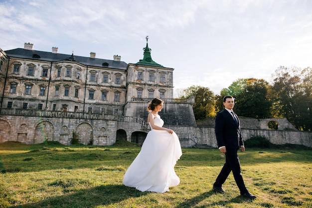 Sposa e sposo al giorno delle nozze camminando all'aperto sul territorio del castello del vecchio palazzo