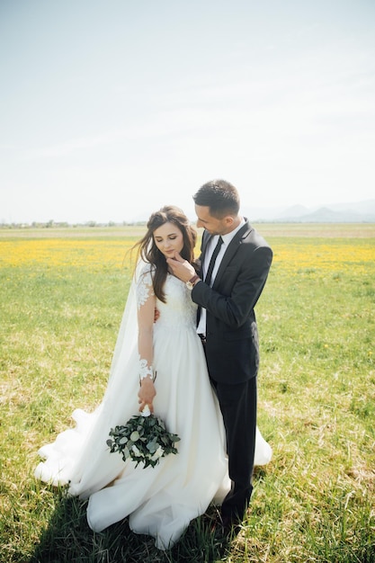 Sposa e sposo al giorno delle nozze camminando all'aperto sulla natura verde d'estate.