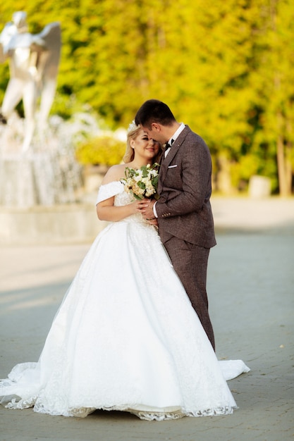 Sposa e sposo al giorno delle nozze che camminano all'aperto sulla natura della molla. Coppia di sposi, sposi felici donna e uomo che abbraccia nel parco verde. Coppia di innamorati matrimonio all'aperto.