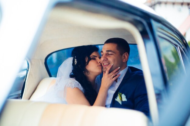 Sposa e sposo all'interno di un'auto classica. Loro sono felici.