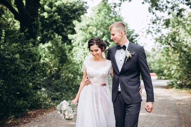 Sposa e sposo che abbracciano, baciano all'aperto in un giorno di nozze, giovane coppia, San Valentino