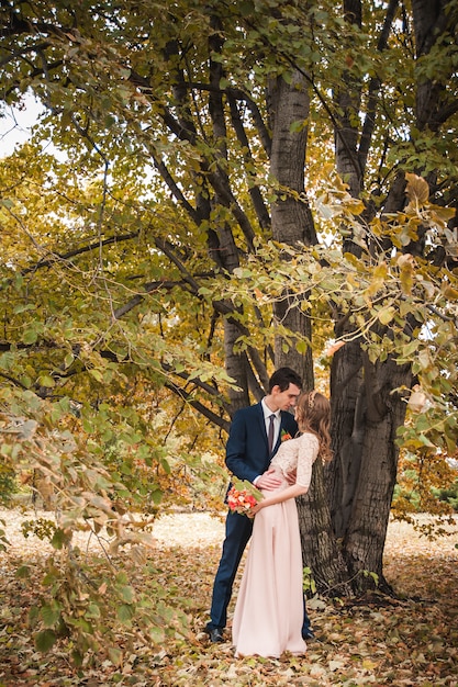 Sposa e sposo che abbracciano in una foresta nella foresta di autunno